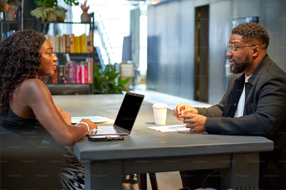 a man and a woman sitting at a table with a laptop