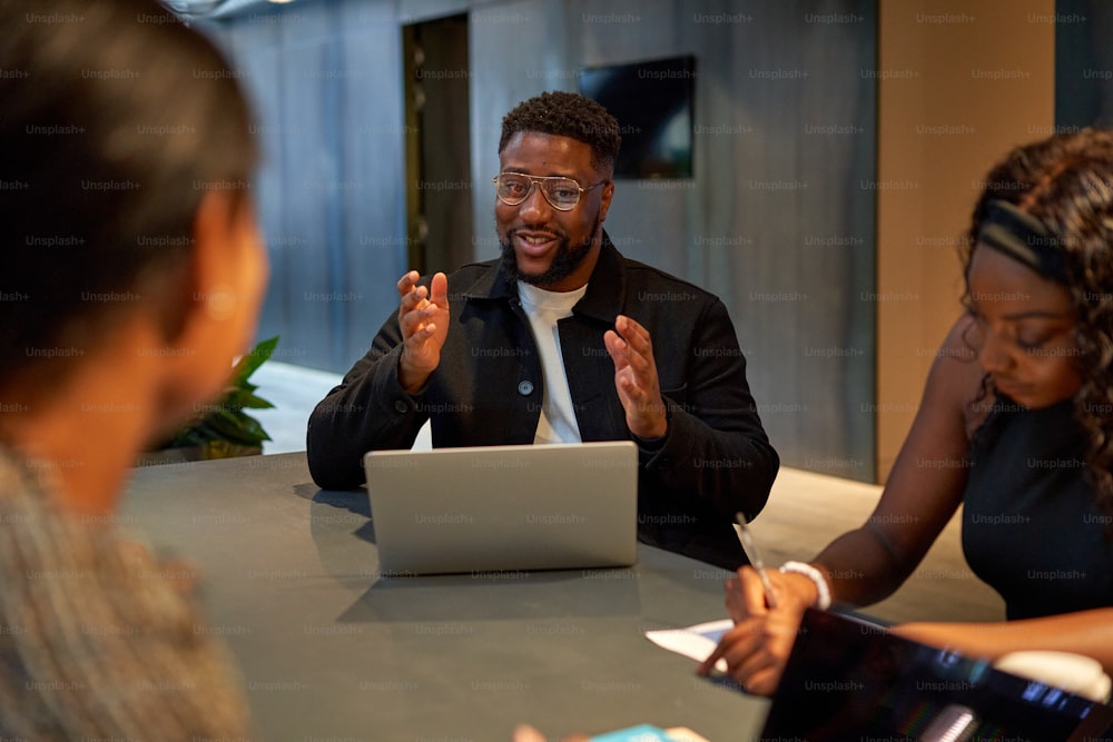 a group of people sitting around a table with a laptop