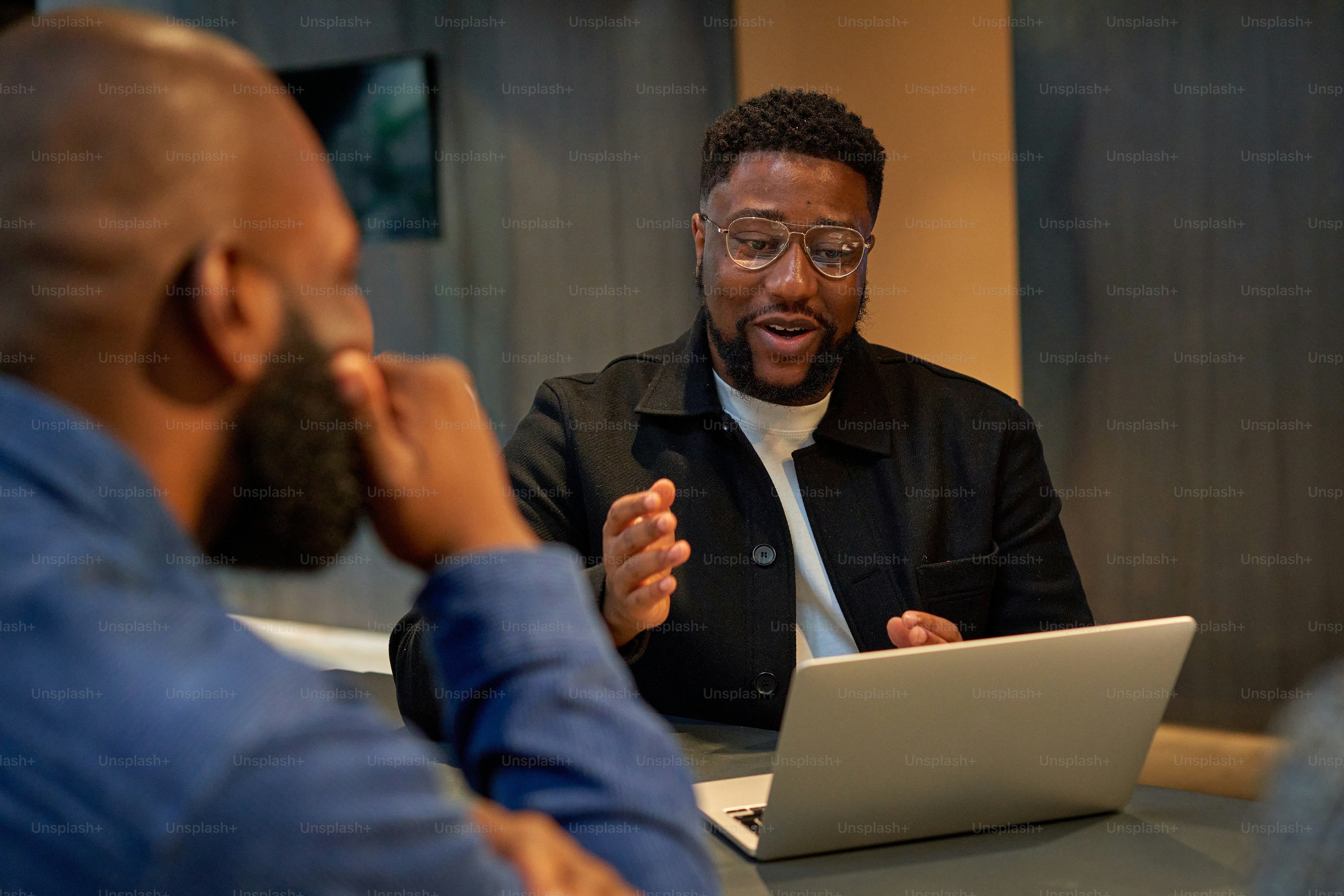 Un hombre sentado en una mesa frente a una computadora portátil