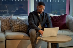 a man sitting on a couch using a laptop computer