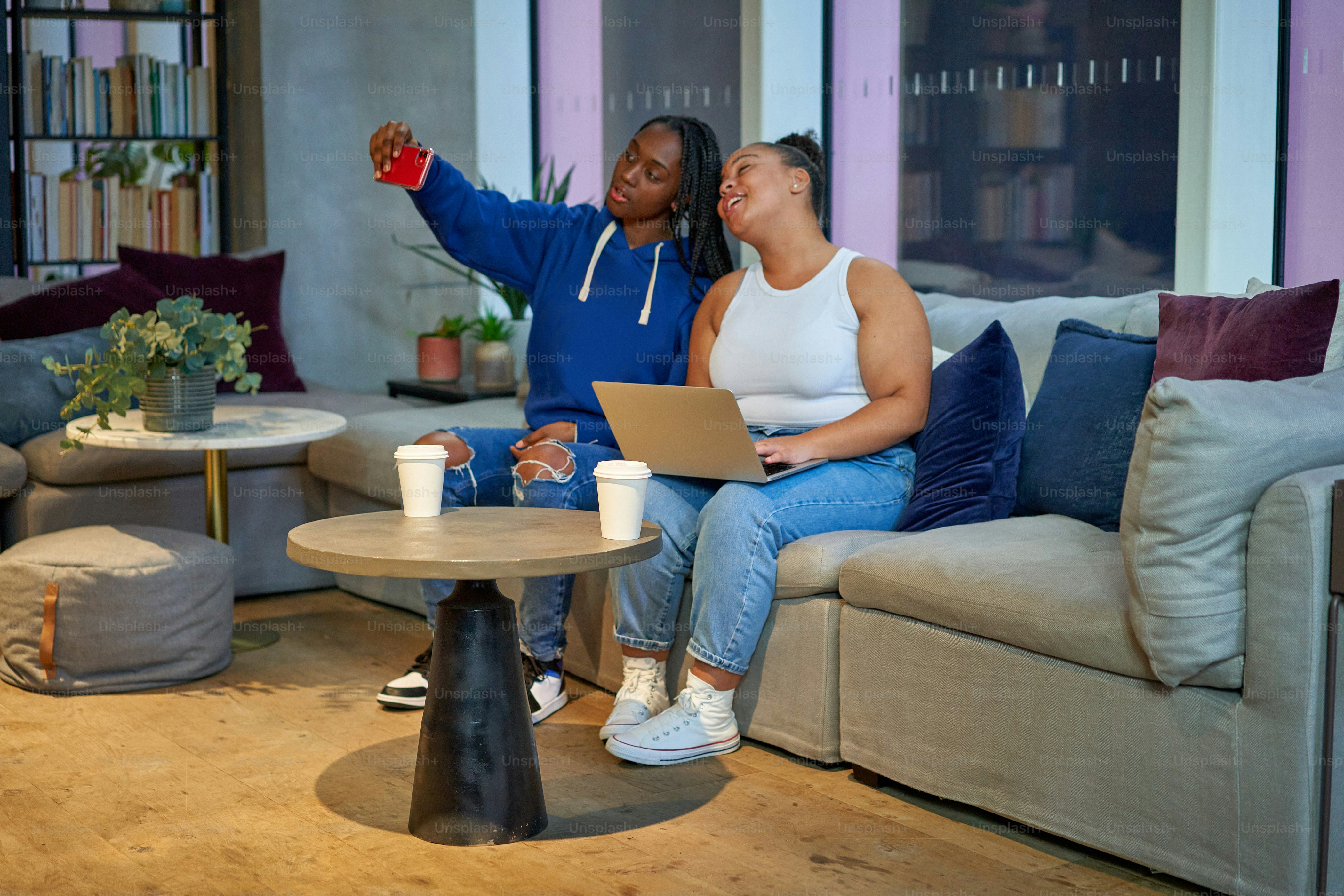 Un par de mujeres sentadas encima de un sofá