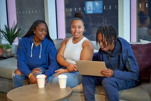 three women sitting on a couch looking at a tablet