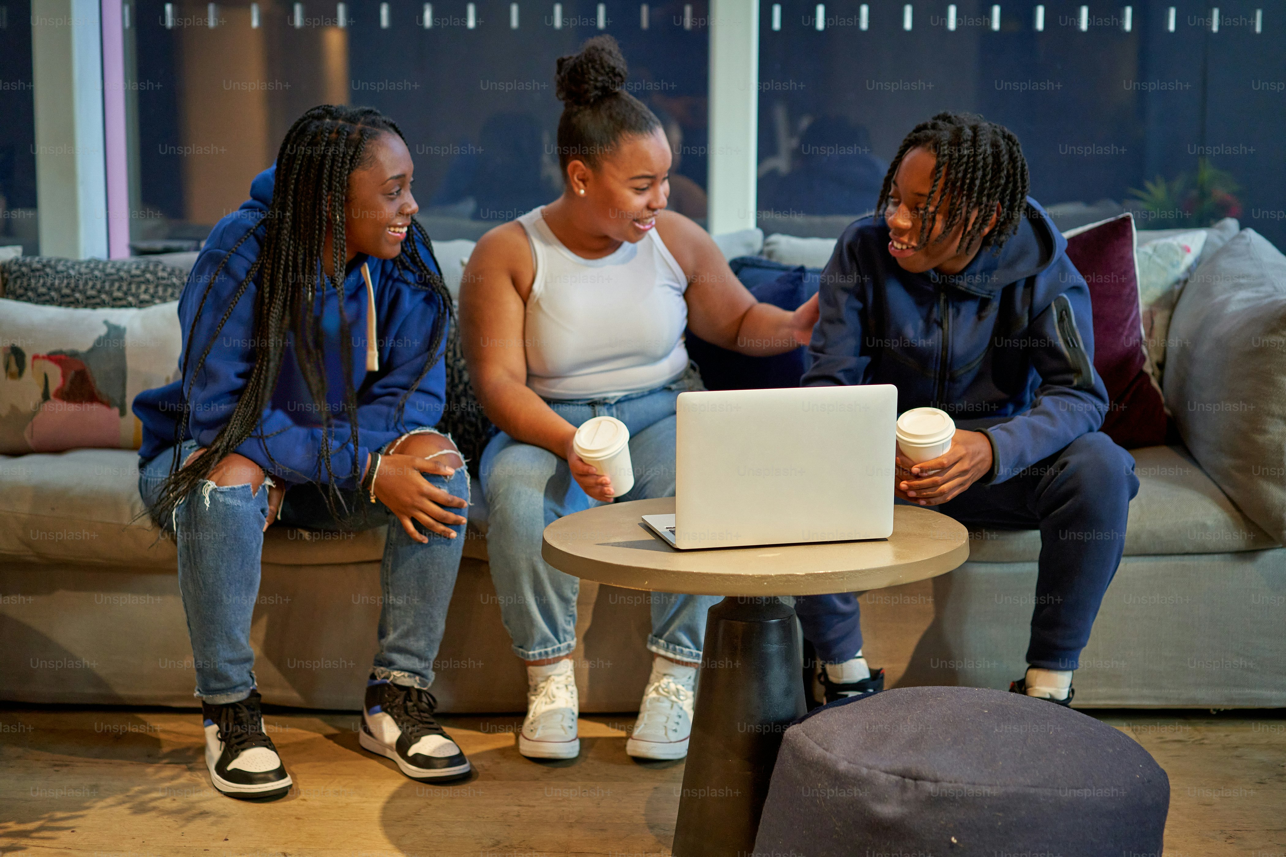 Tres mujeres sentadas en un sofá mirando una computadora portátil