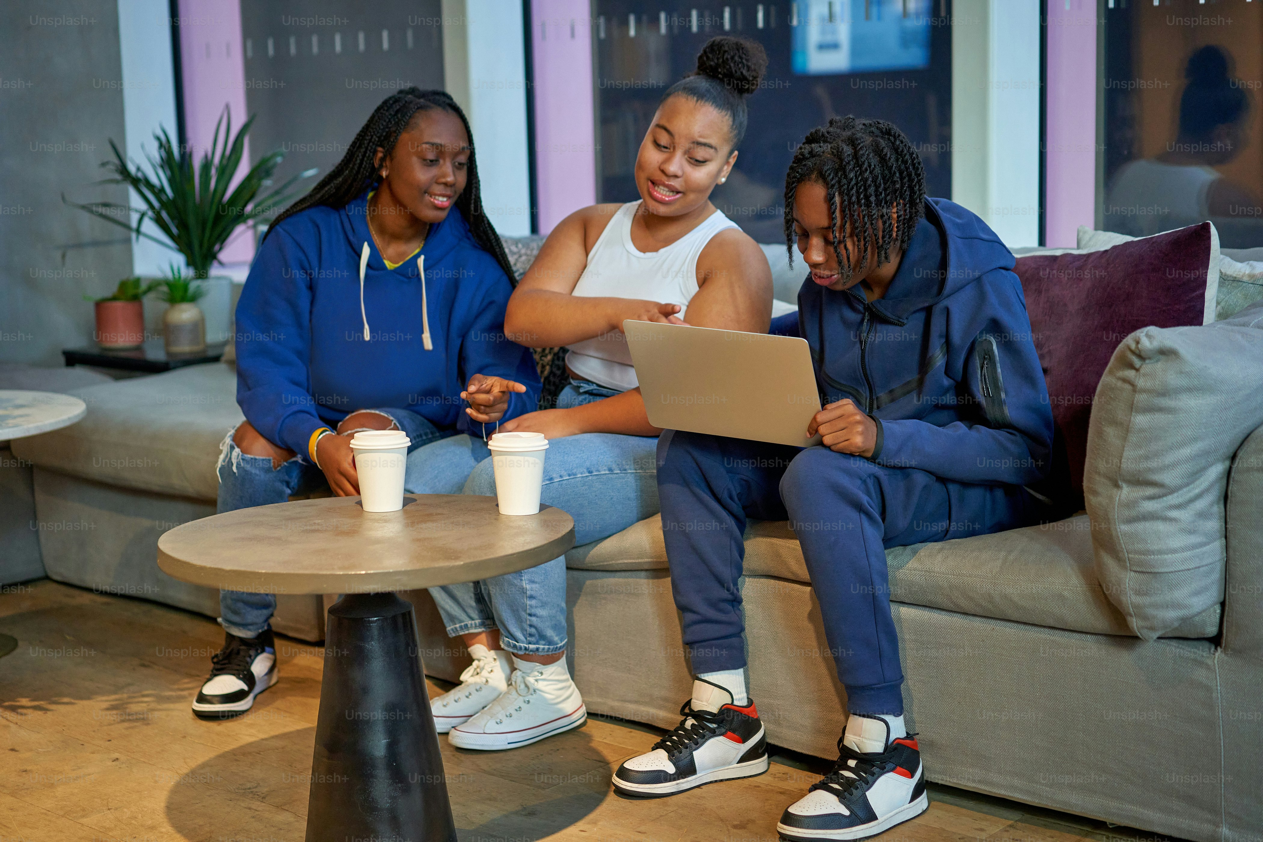 three women sitting on a couch looking at a laptop