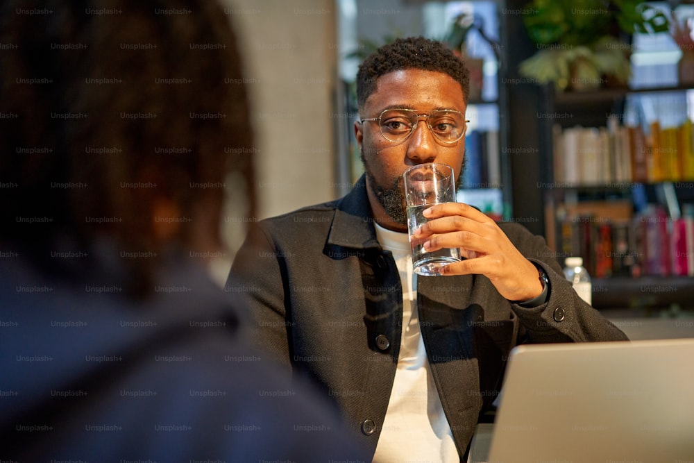 Un hombre sentado en una mesa con un vaso de agua frente a él