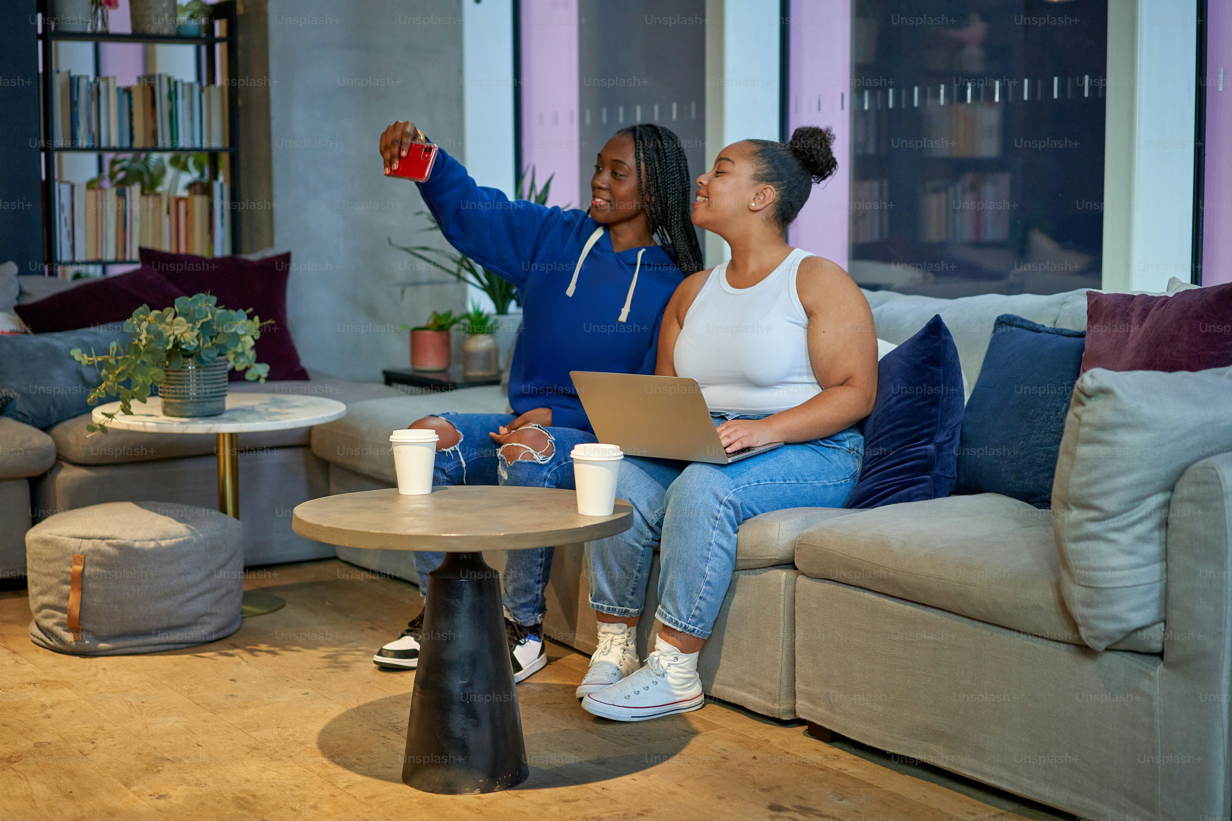 Un par de mujeres sentadas encima de un sofá