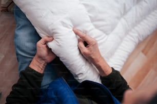 a person holding a pillow on top of a bed