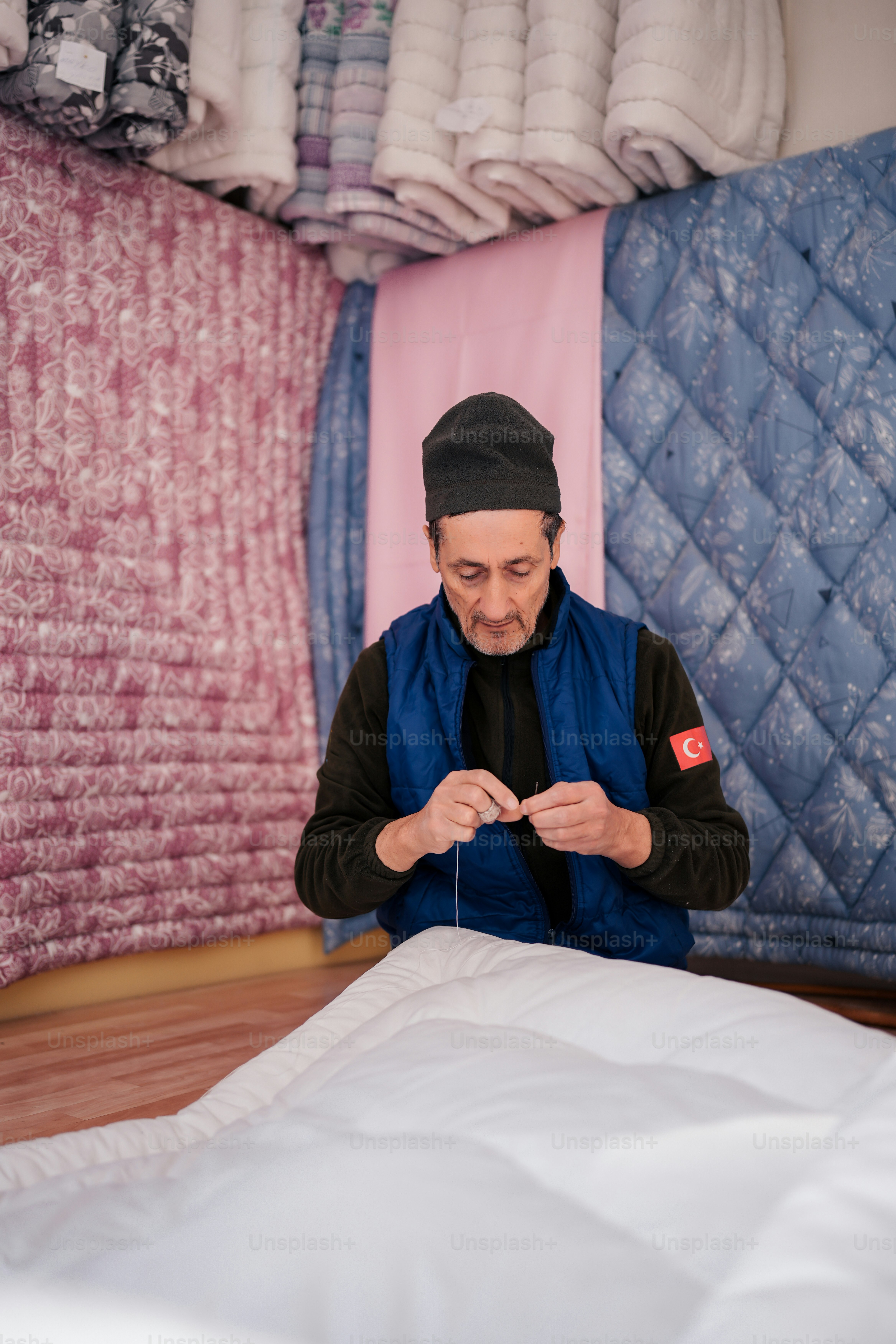 a man sitting on the floor working on a piece of fabric