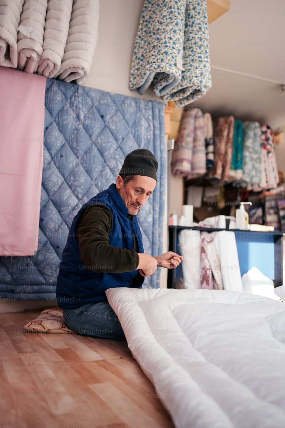 a man sitting on the floor working on a mattress