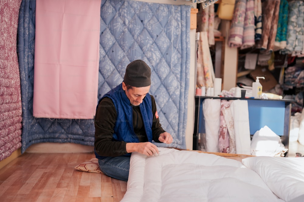 a man sitting on the floor working on a quilt