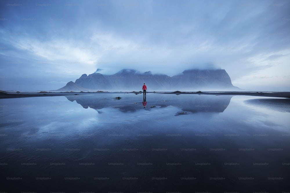 Una persona in piedi su una spiaggia con una montagna sullo sfondo