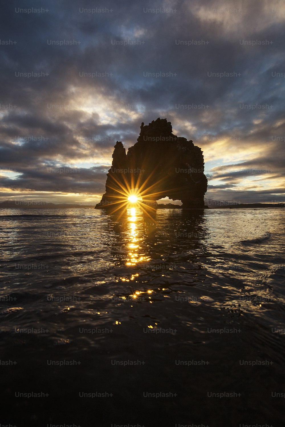 Il sole sta tramontando dietro una roccia nell'oceano