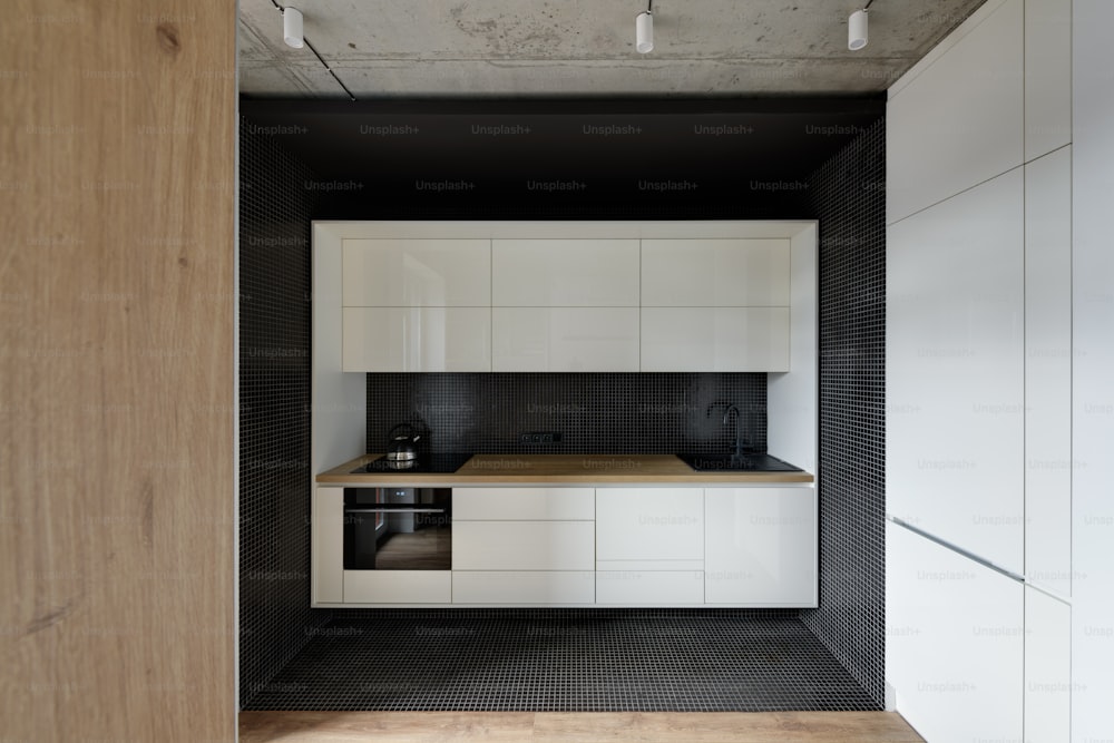 uma cozinha com armários brancos e bancadas pretas