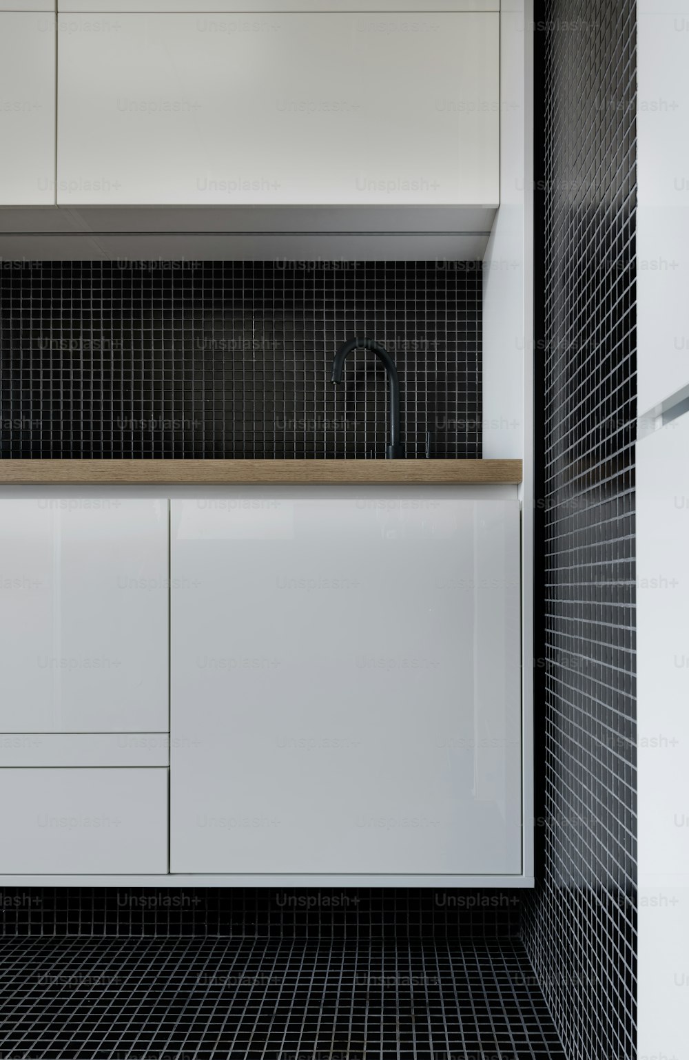 una cocina con armarios blancos y suelo de baldosas negras