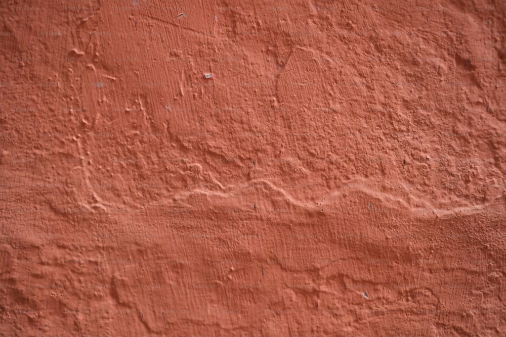 a red stucco wall with a small patch of paint on it