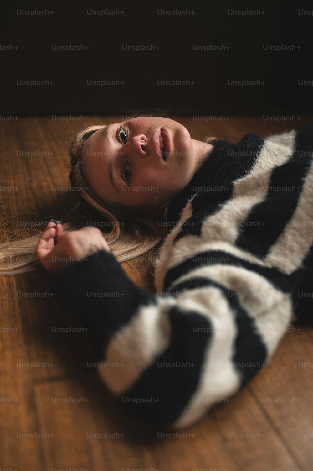 a woman laying on the floor wearing a black and white sweater