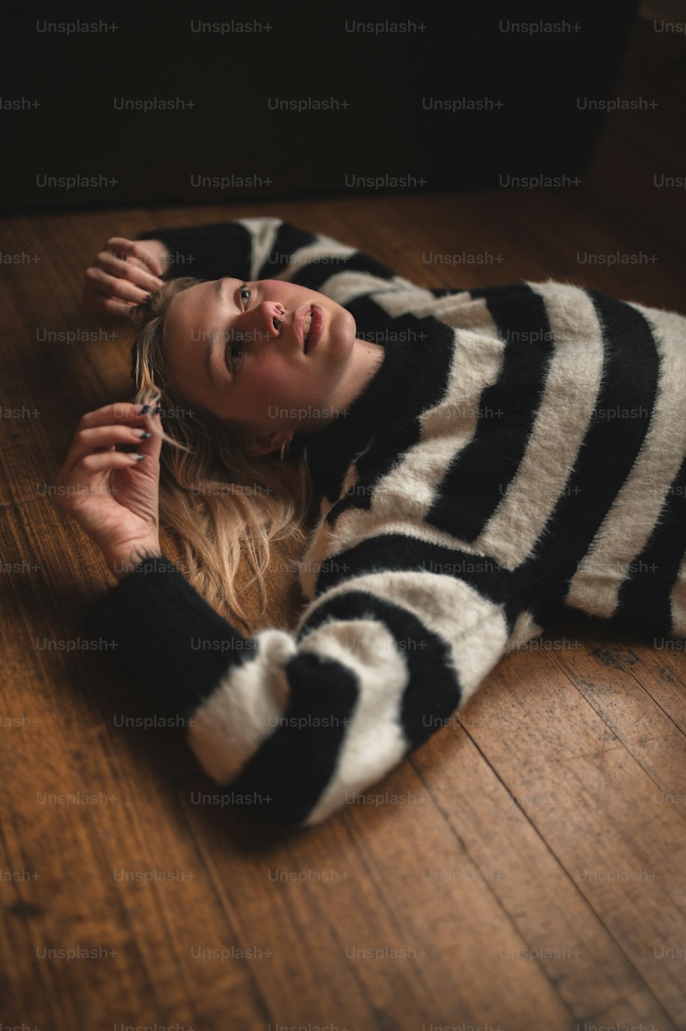 a woman laying on the floor wearing a striped sweater