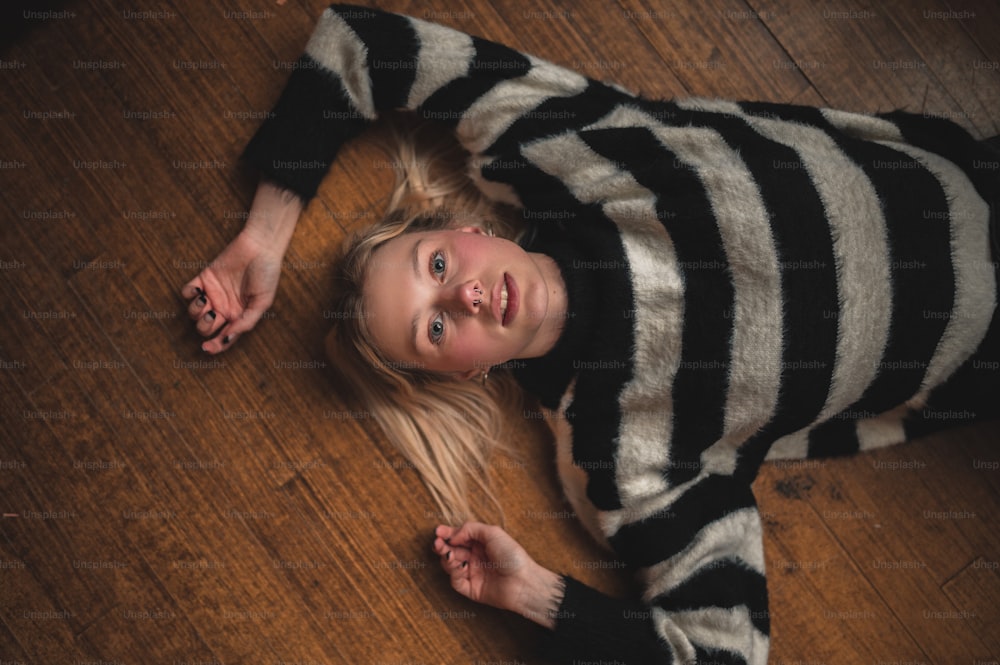 a little girl laying on the floor wearing a striped shirt