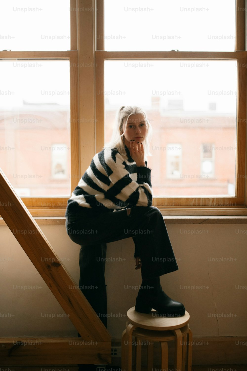 a woman sitting on a stool in front of a window