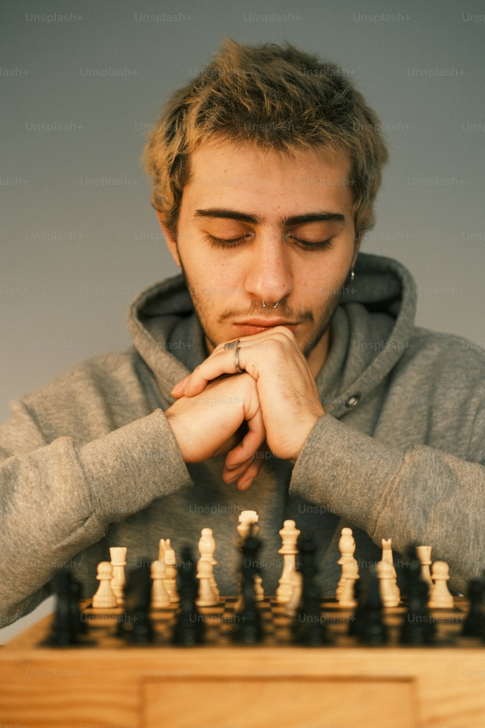 Young pensive man sitting and playing chess online