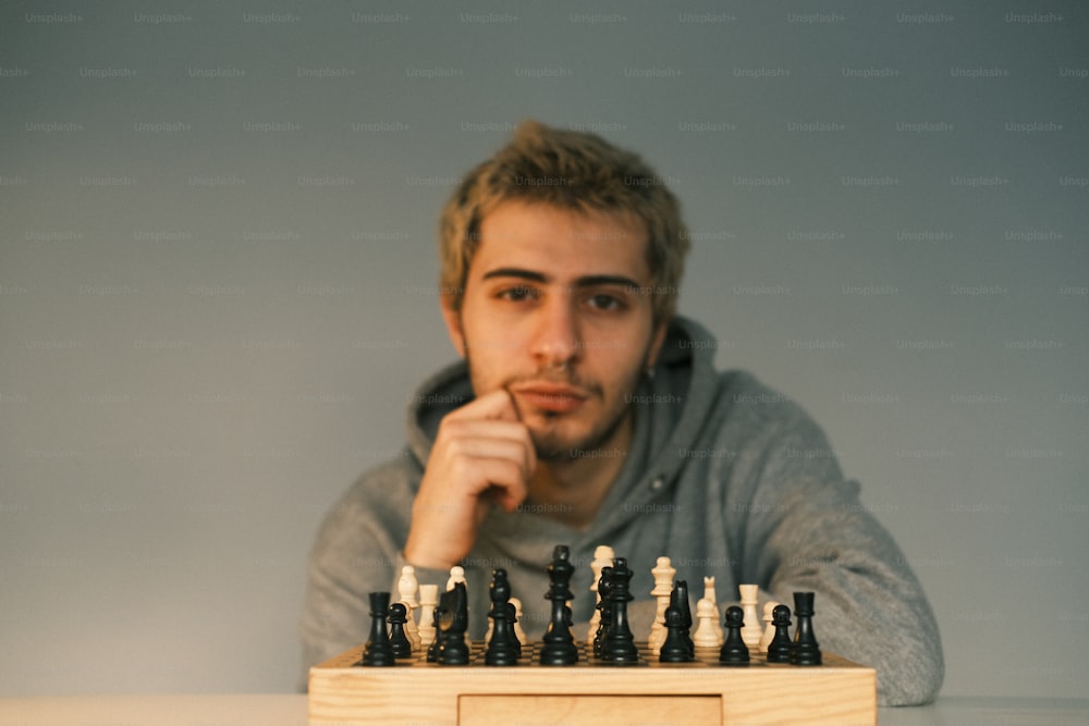 um homem sentado na frente de um tabuleiro de xadrez