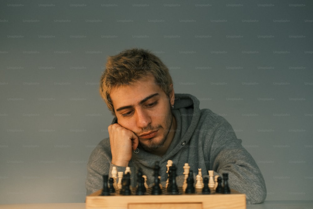 um homem sentado em uma mesa com um tabuleiro de xadrez