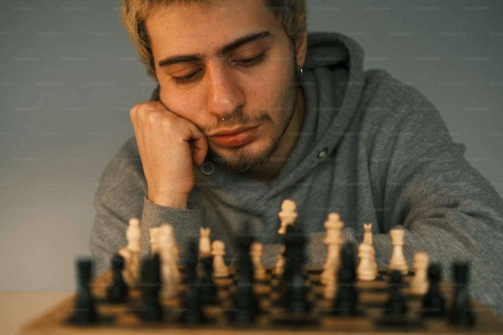 um homem sentado na frente de um tabuleiro de xadrez