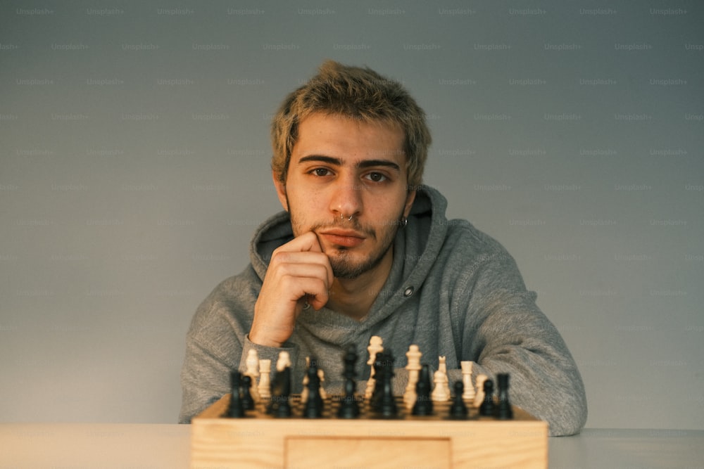 Un hombre sentado en una mesa con un tablero de ajedrez