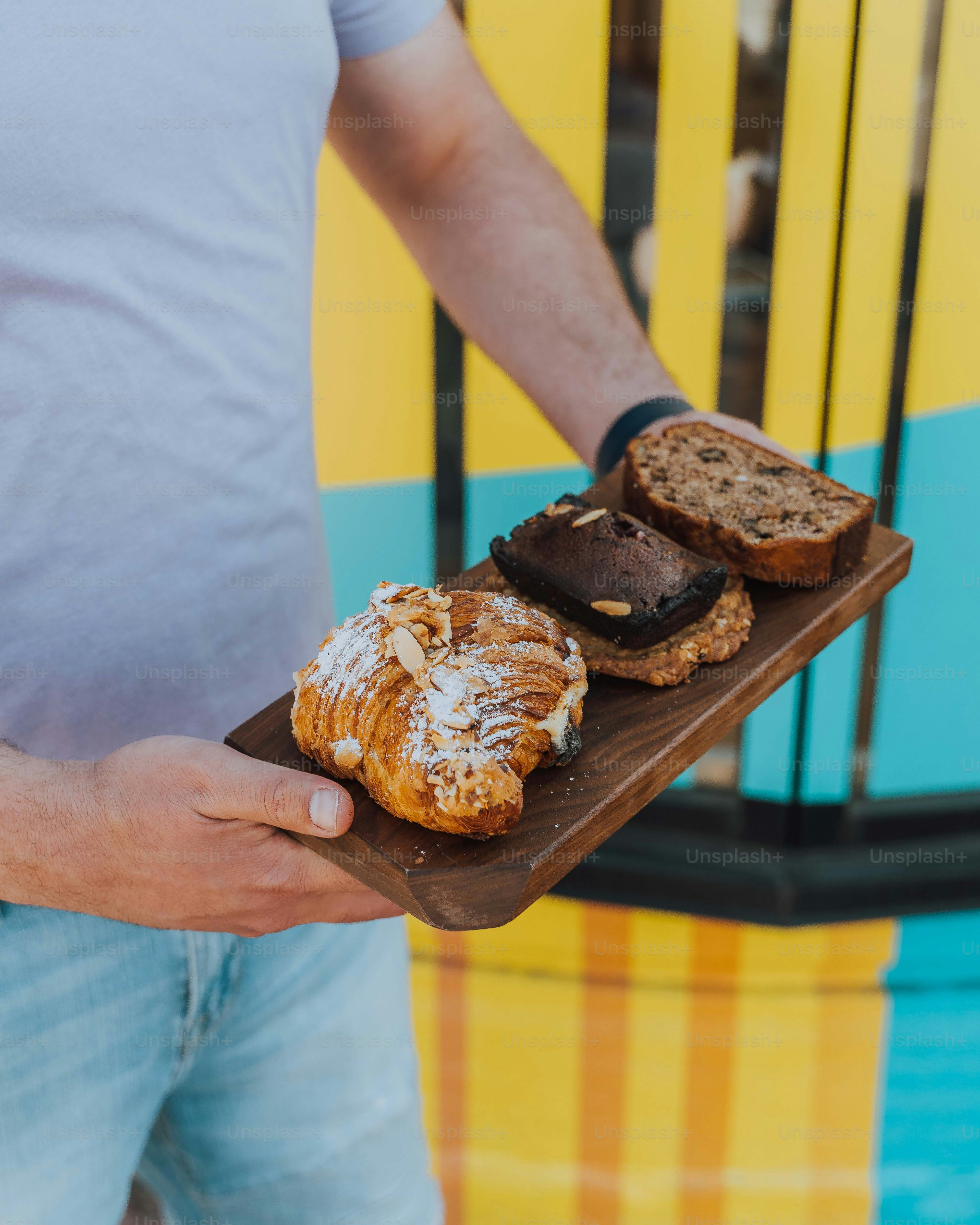 a man is holding a tray of pastries