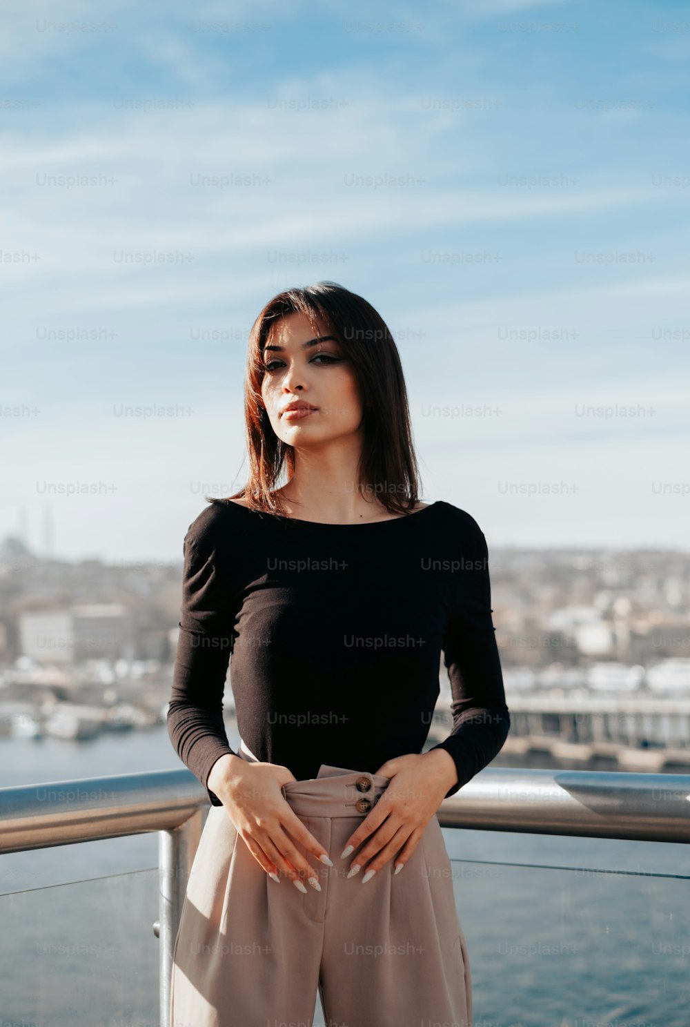 a woman standing on a balcony next to a body of water