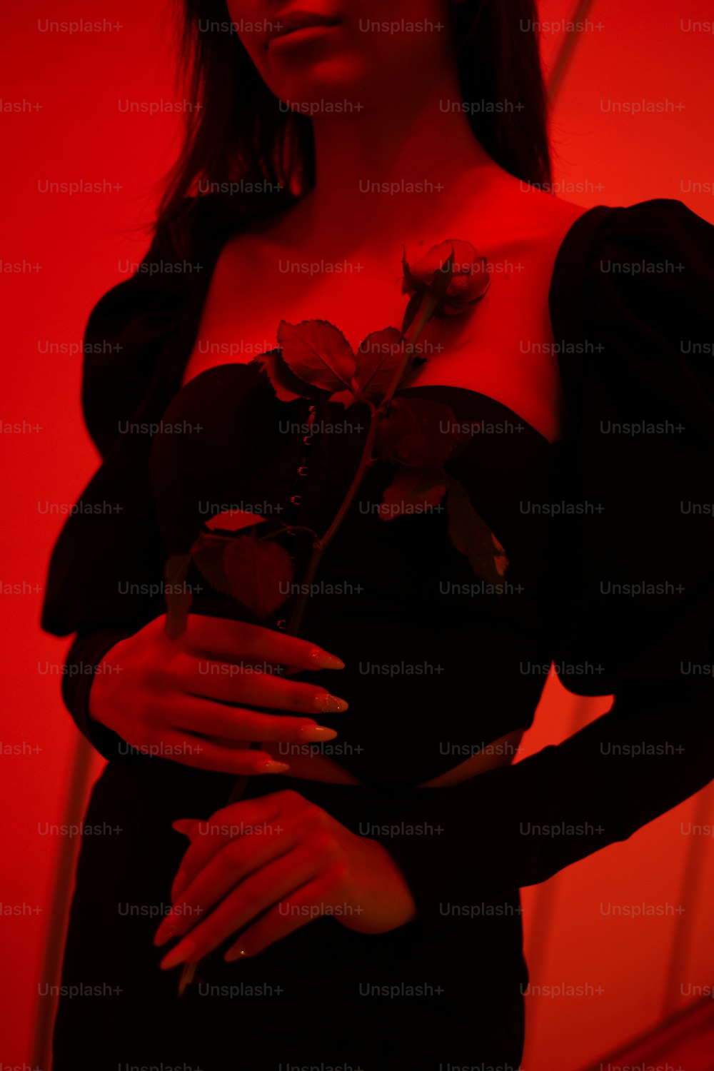 Eine Frau in einem schwarzen Kleid, die eine Rose hält