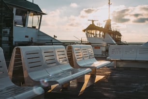a row of white benches sitting on top of a pier