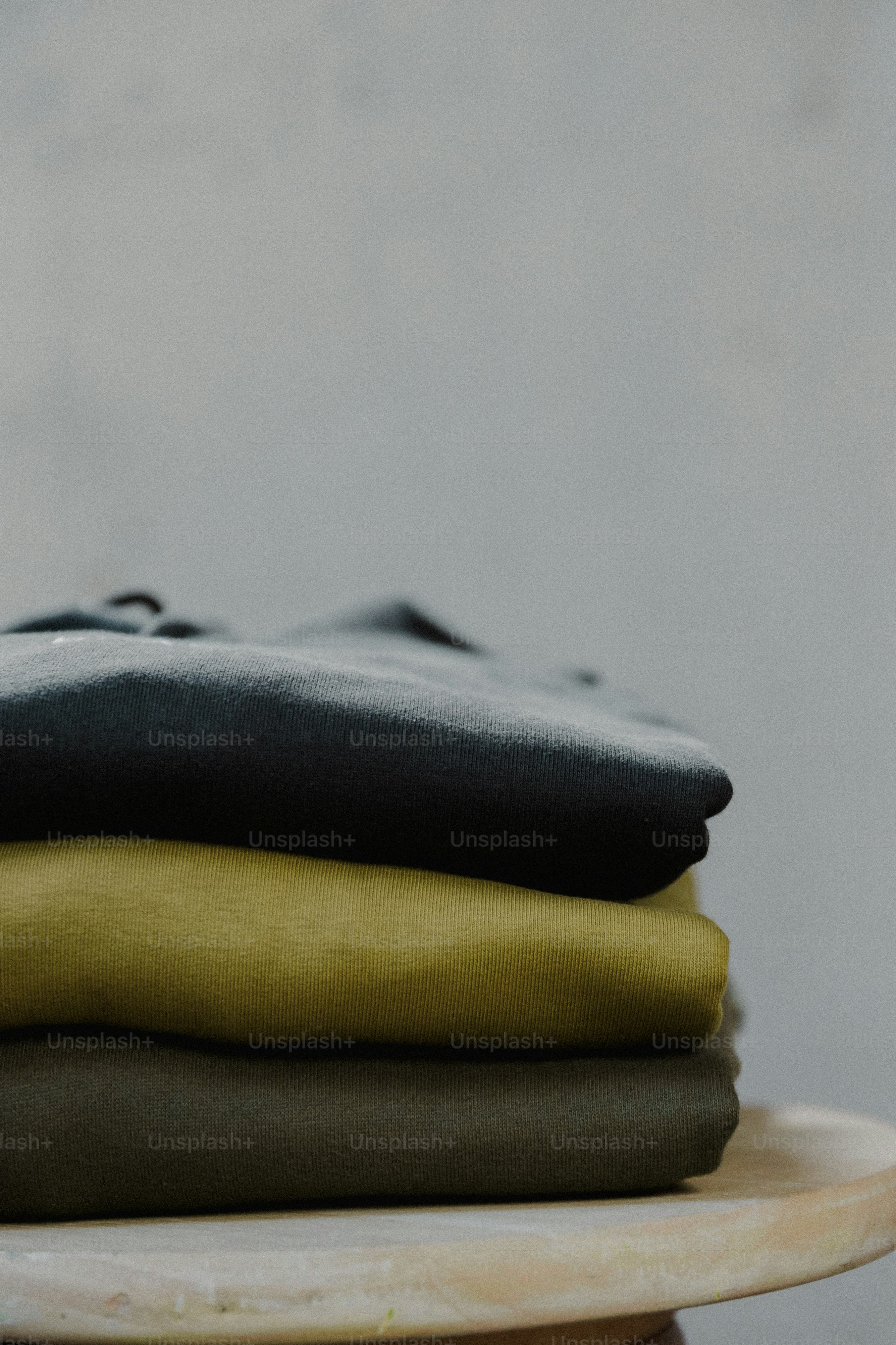 a stack of folded clothes sitting on top of a wooden table