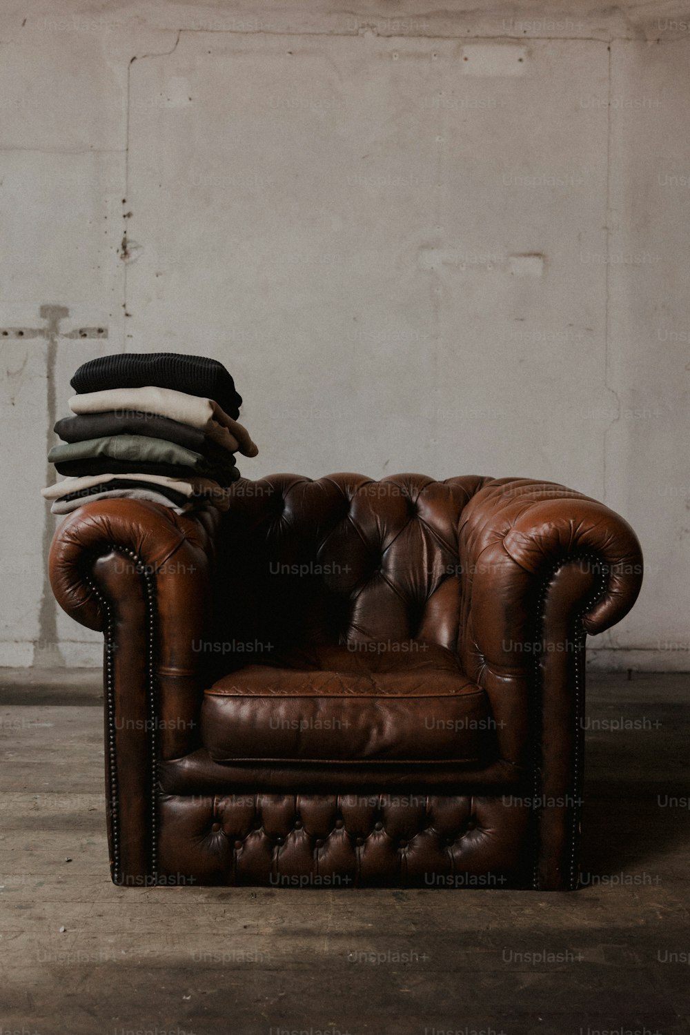 a brown leather chair with a pile of blankets on top of it