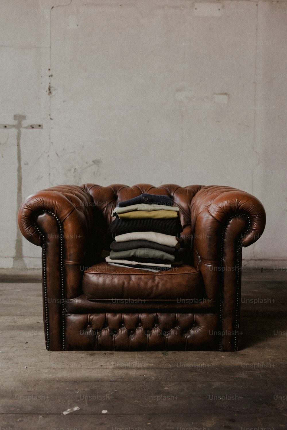 una silla de cuero marrón con una pila de almohadas encima.