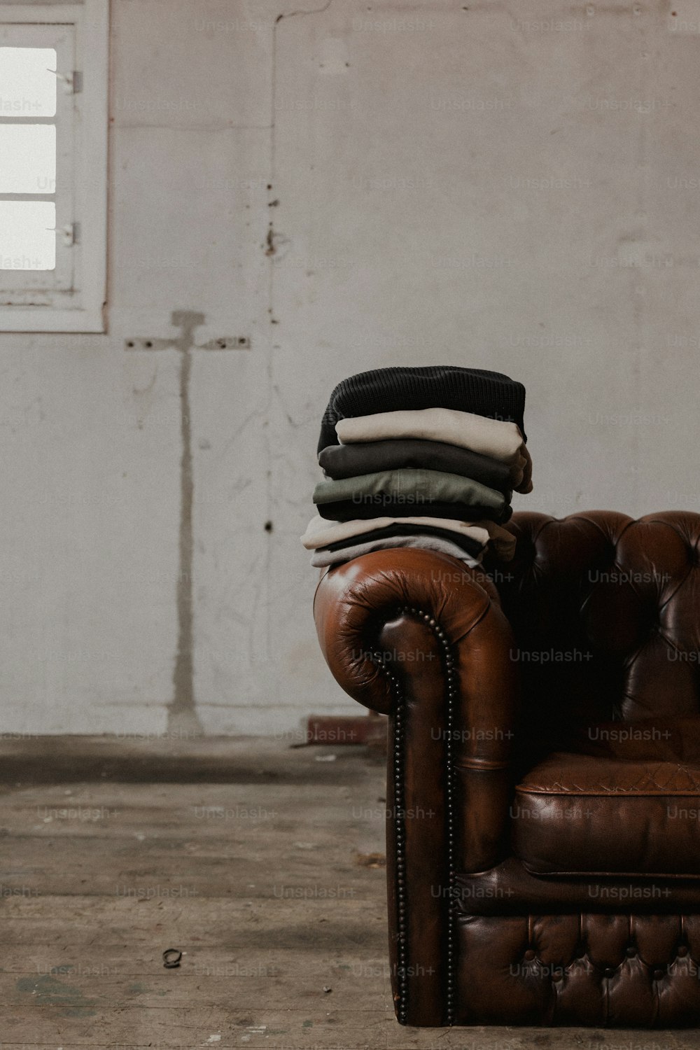 uma cadeira de couro com uma pilha de roupas dobradas em cima dela