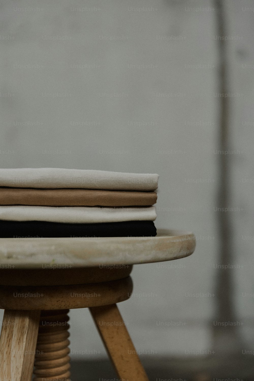 a close up of a wooden stool with a stack of cloth on top of it