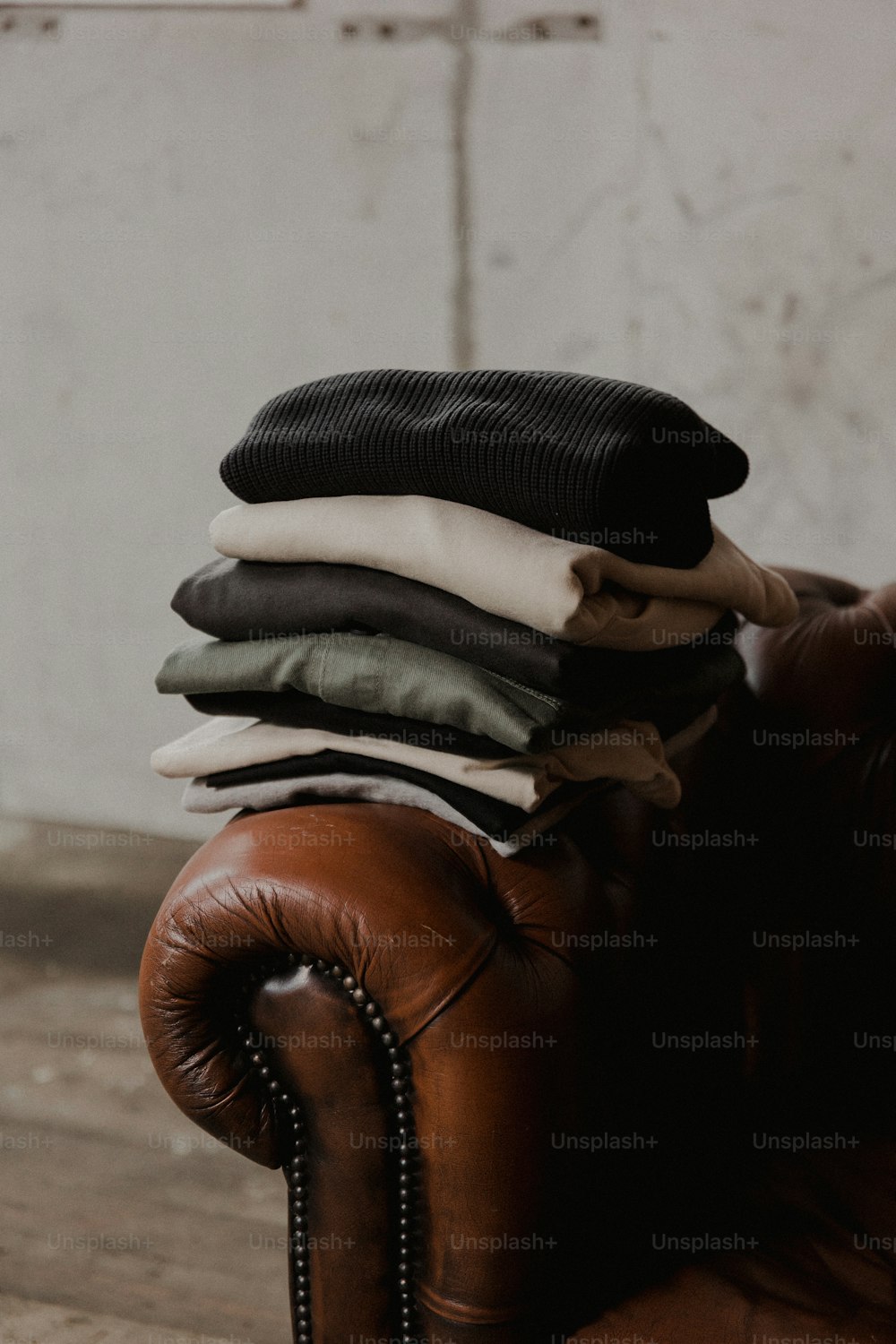 Un montón de ropa sentada encima de una silla de cuero