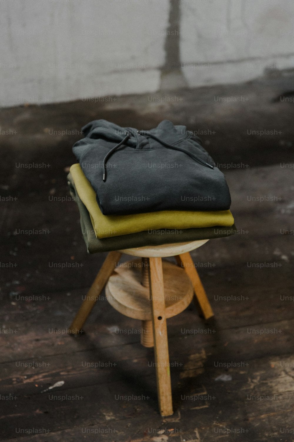 a stack of folded clothes sitting on top of a wooden stool