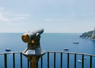 ein Teleskop auf einem Geländer mit Blick auf ein Gewässer