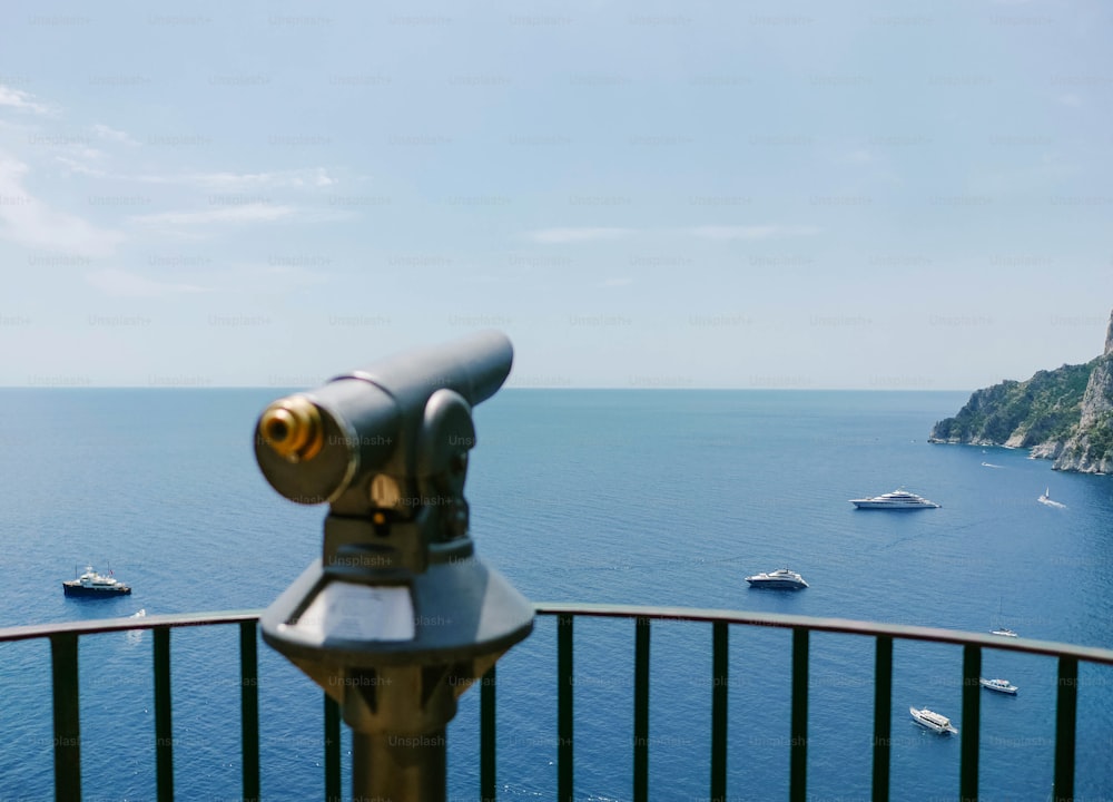 a telescope on a railing overlooking a body of water