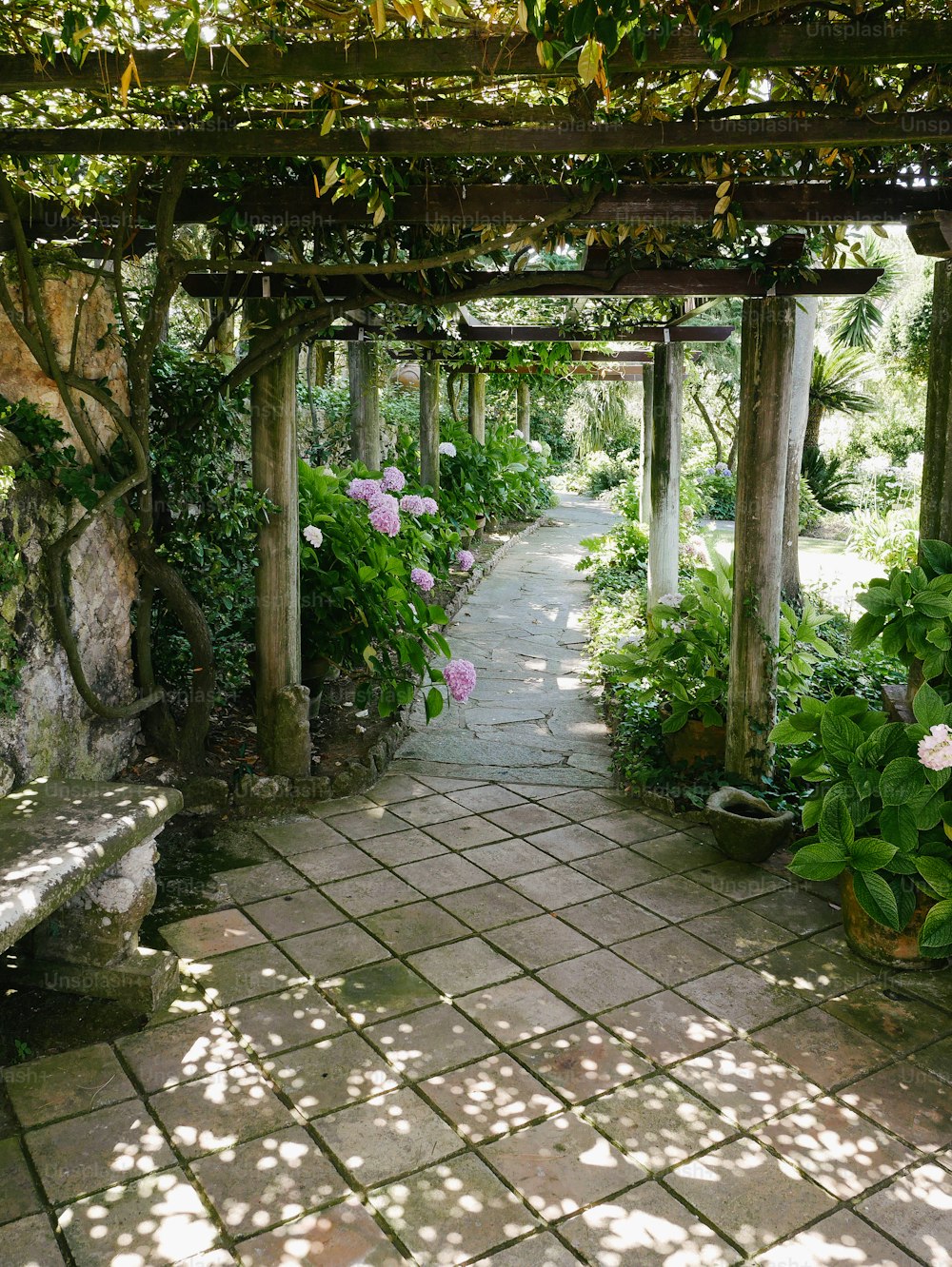 a stone walkway with a bench and flowers