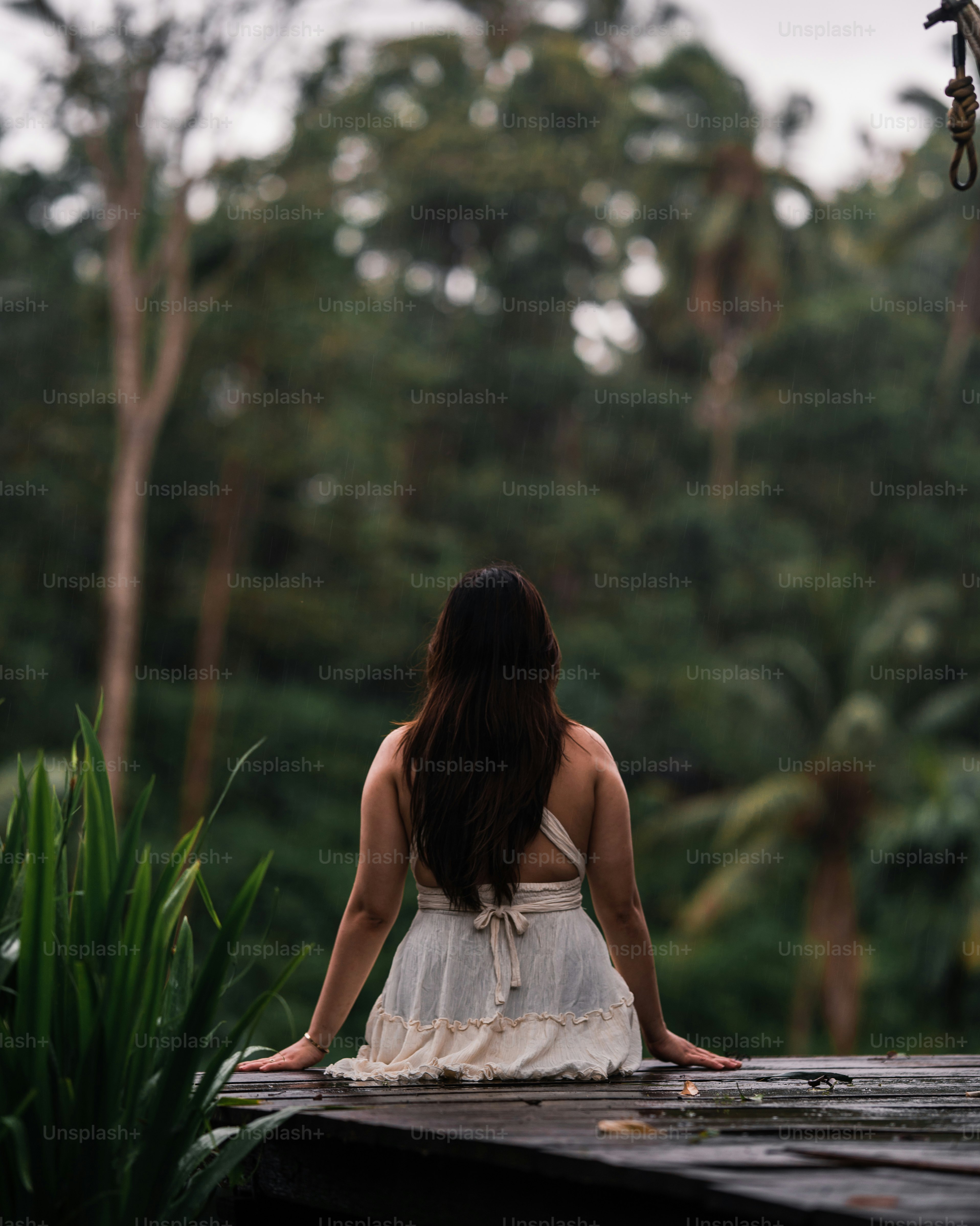 a woman in a white dress sitting on a dock