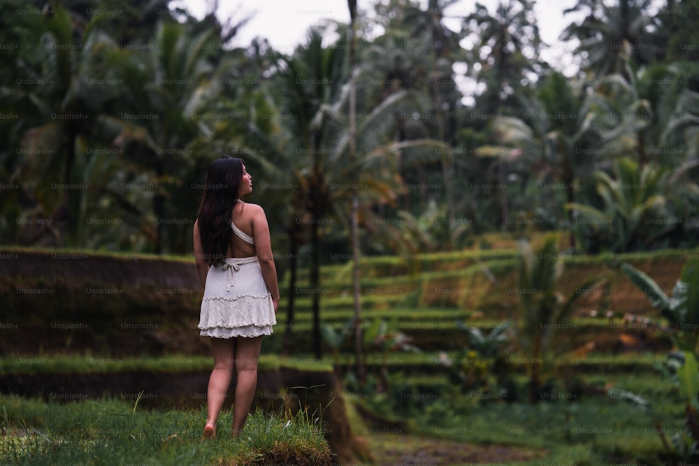 a woman in a white dress standing in a field