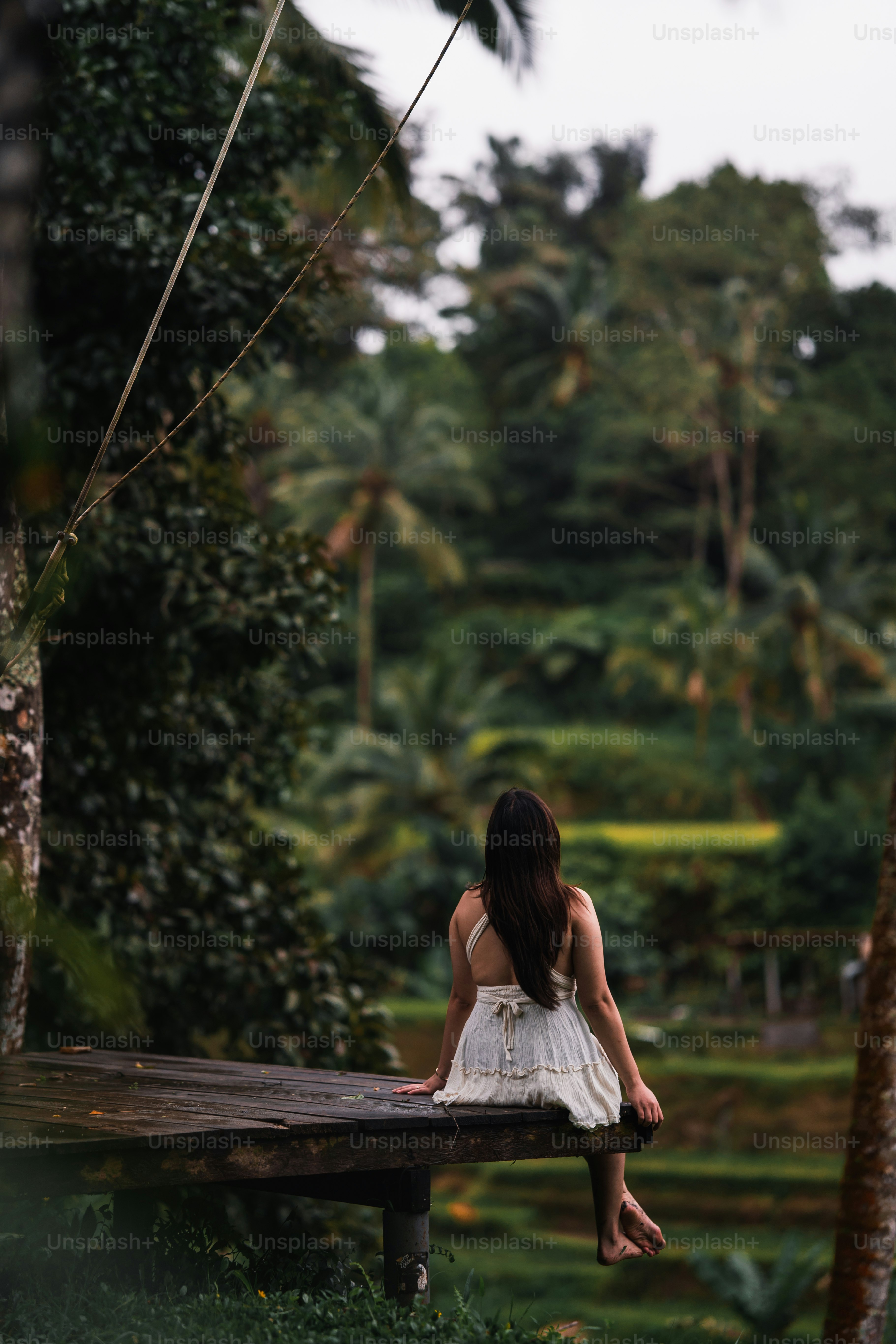a woman in a white dress sitting on a wooden bench