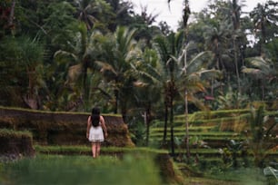 Une femme en robe blanche marchant dans un champ verdoyant