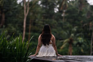 a woman in a white dress sitting on a dock