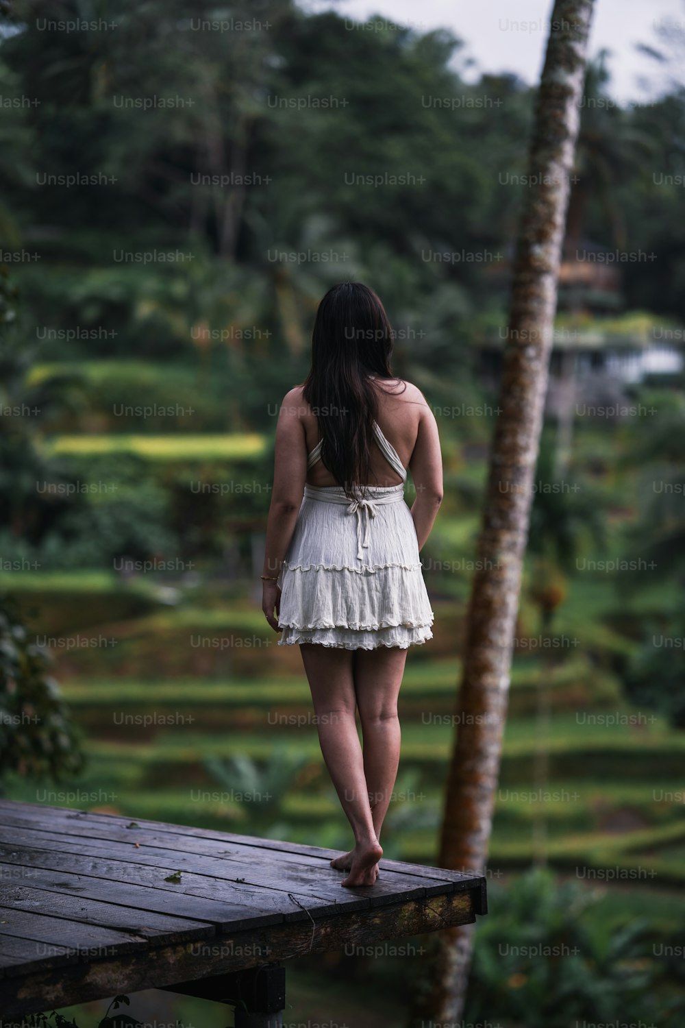 uma mulher em um vestido branco de pé em uma plataforma de madeira