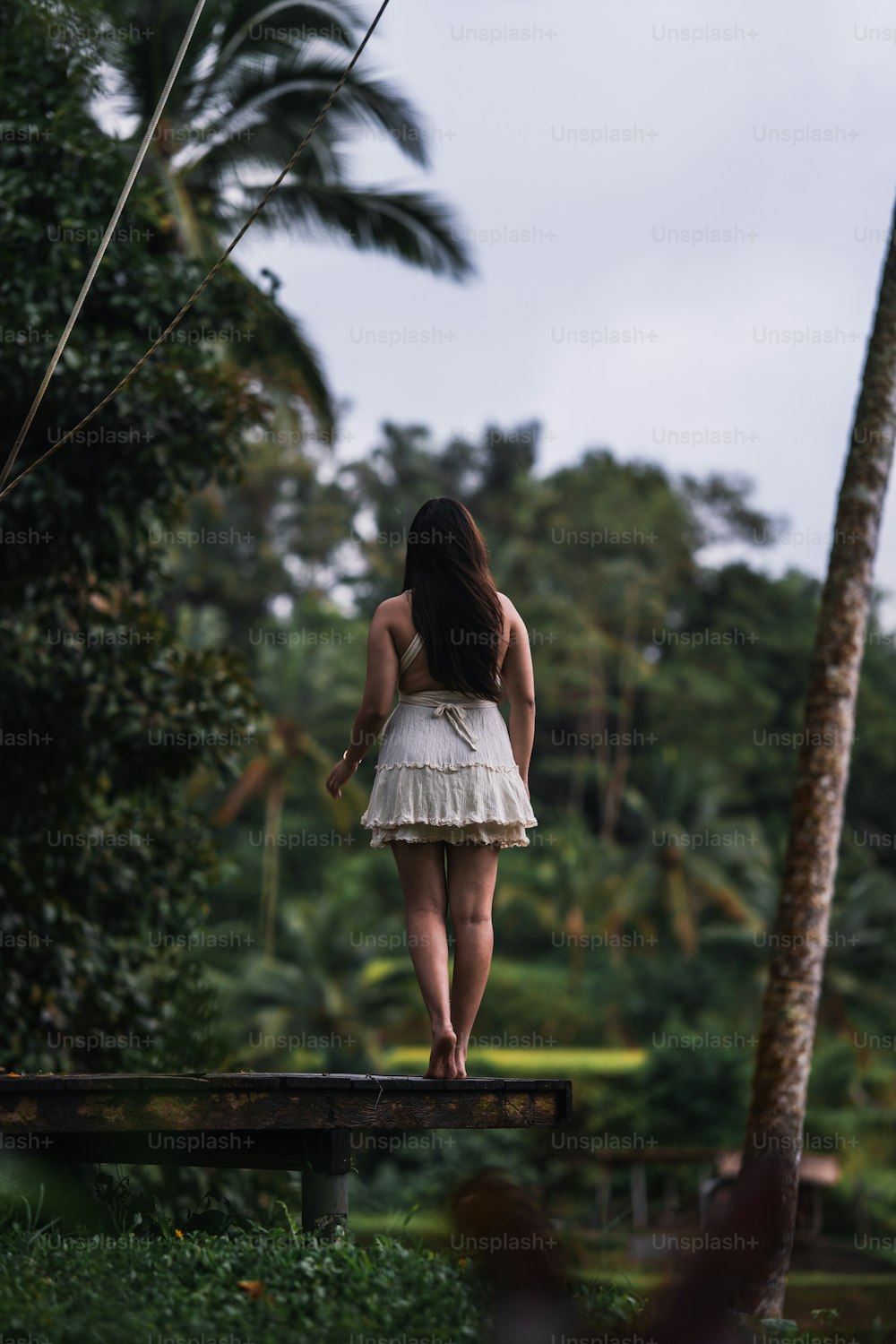 a woman in a white dress standing on a bench