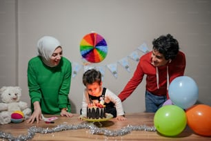 Una mujer y dos niños soplando velas en un pastel